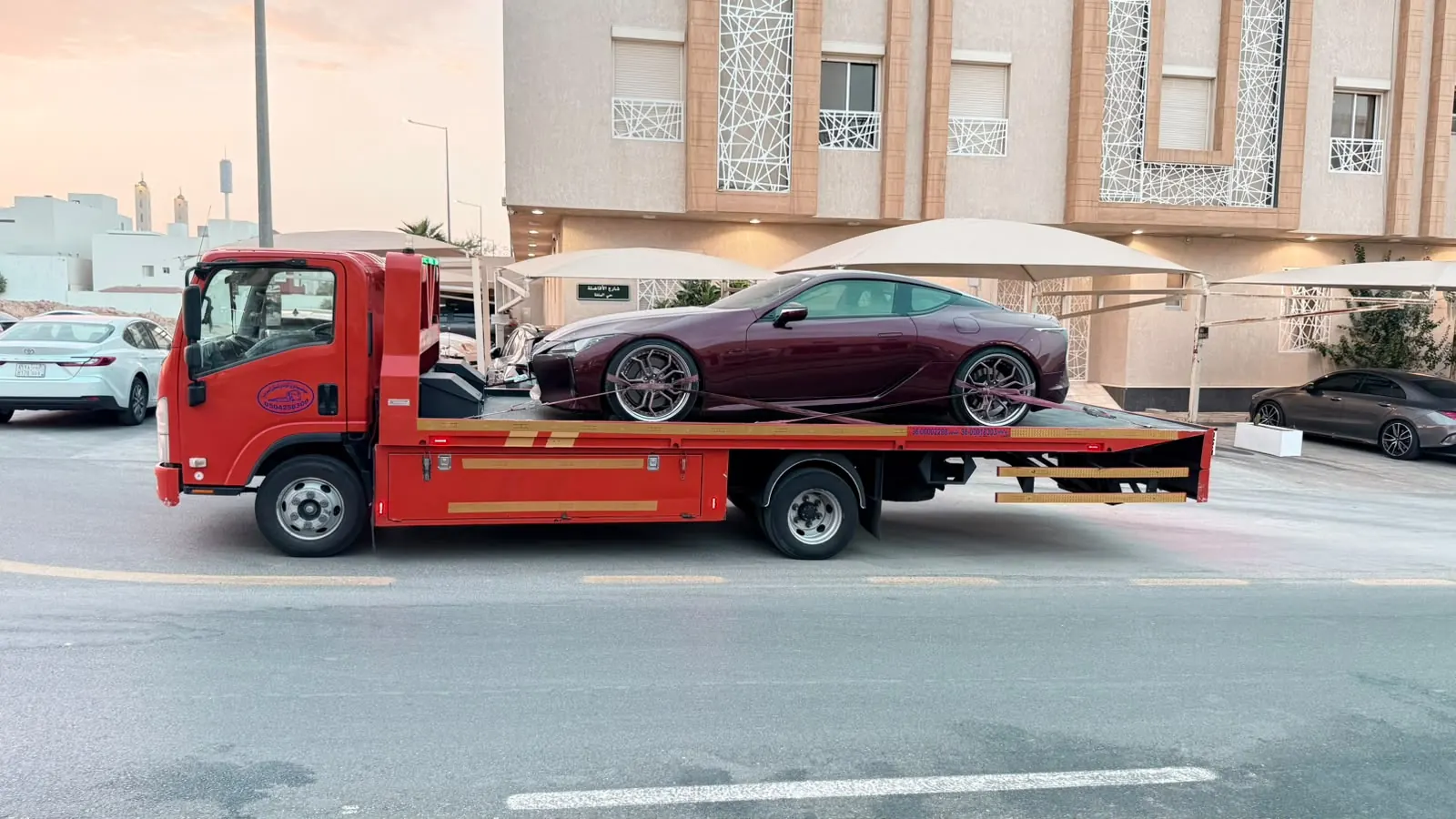 خدمة سطحة VIP لنقل سيارة لكزس LC 500 فاخرة أمام مبنى سكني حديث
